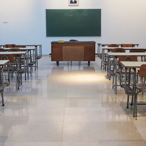 Empty classroom with rows of desks facing a chalkboard